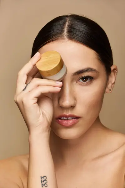 Beautiful young woman gently holds a skincare jar against her forehead, exuding tranquility. — Stock Photo