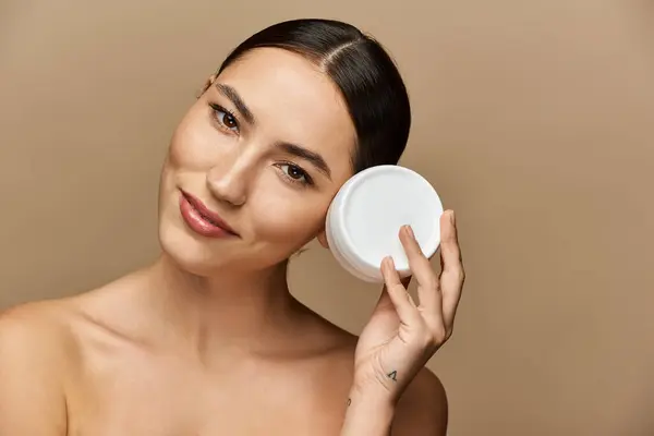 Young brunette applies skincare, smiling and exuding confidence and charm. — Stock Photo