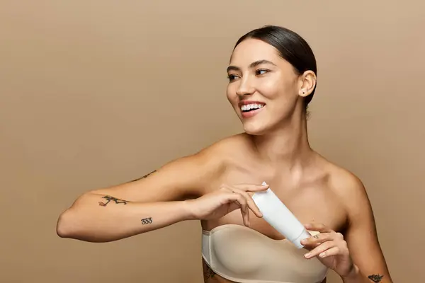 A young beautiful woman applies a skincare product while smiling, exuding joy and radiance. — Stock Photo
