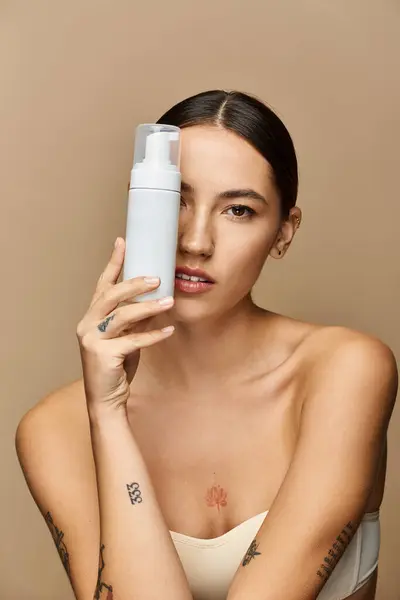 Brunette woman with flawless skin highlights a skincare product while exuding elegance and beauty. — Stock Photo