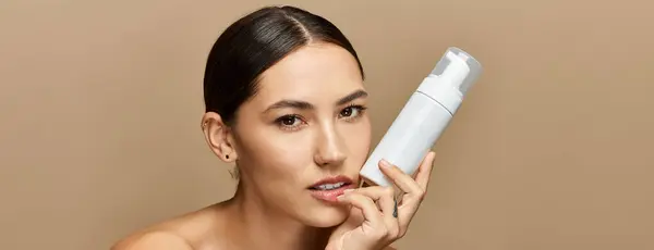 Young brunette woman highlights a skincare product while posing with confidence and elegance. — Stock Photo