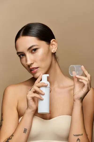 Young beautiful woman holds a skincare bottle and applicator, radiating confidence and beauty. — Stock Photo
