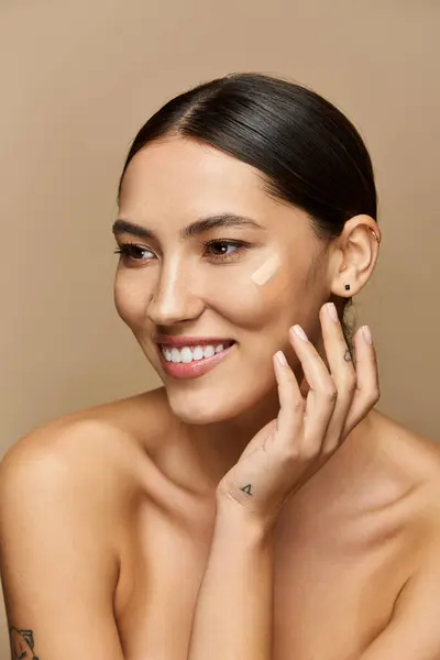 Brunette woman smiles warmly while applying makeup against a neutral backdrop. — Stock Photo