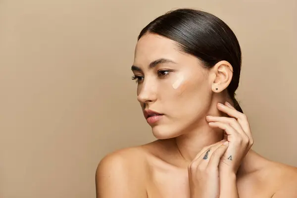 Brunette woman touches her neck softly, highlighting her radiant skin in warm lighting. — Stock Photo