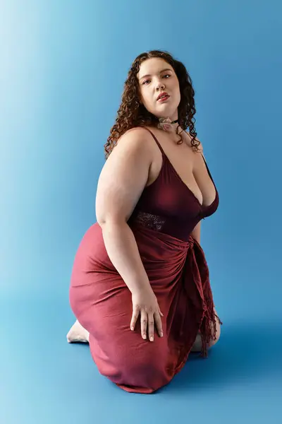 A beautiful young woman showcases her fashion sense in a maroon dress while posing elegantly. — Stock Photo