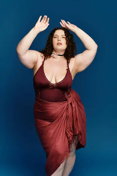 Fashionable young woman expresses confidence with graceful poses in a striking blue backdrop. — Stock Photo
