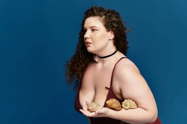 A young woman showcases her trendy outfit while holding beautiful decorative shells with poise. — Stock Photo