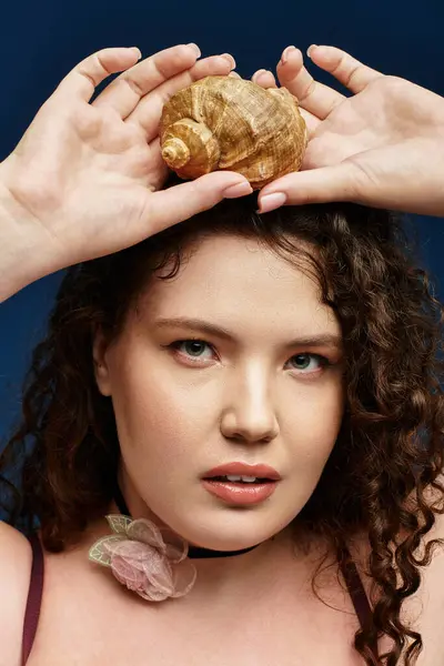 A stylish young woman poses confidently with a seashell balanced on her head, radiating beauty. — Stock Photo