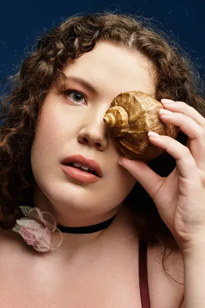 Beautiful young woman creating an artistic expression using a shell in an indoor space. — Stock Photo