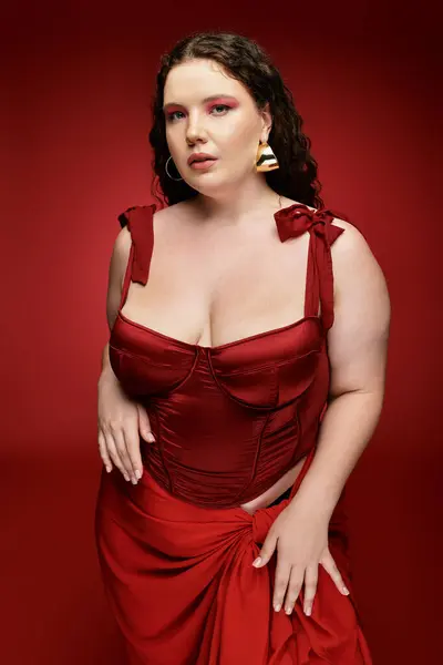 Young woman in bold red outfit poses confidently against a deep red background. — Stock Photo