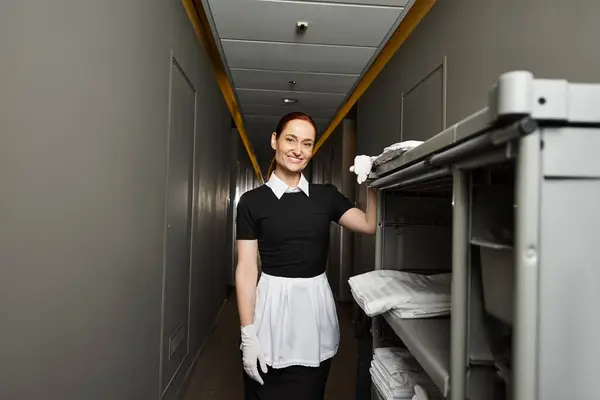 A beautiful young woman in uniform smiles brightly as she prepares for her workday. — Stock Photo