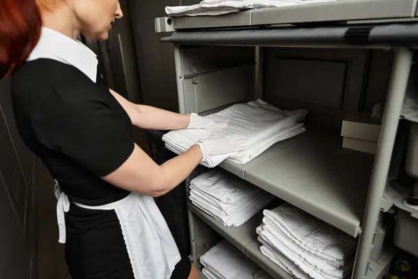 In a chic hotel, a young woman carefully arranges clean towels on shelves with precision. — Stock Photo