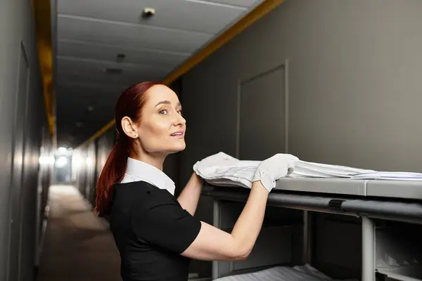 Junge Frau sortiert in der Abenddämmerung sorgfältig saubere Bettwäsche in einem Regal in einem ruhigen Flur — Stockfoto