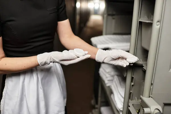 Em uma hora tranquila, uma jovem mulher delicadamente organiza lençóis recém-dobrados em um corredor estreito. — Fotografia de Stock
