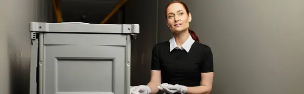 Eine junge Frau mit roten Haaren steht neben einem Vorratsbehälter und demonstriert ihre Professionalität. — Stockfoto