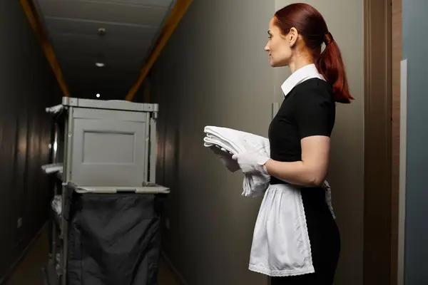 Confident young woman in uniform holds clean towels while readying for her evening shift. — Stock Photo