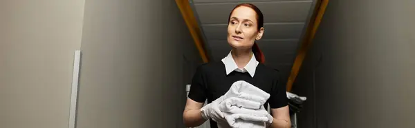 A beautiful young woman walks confidently holding towels in a modern hotel corridor. — Stock Photo