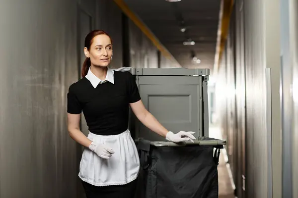 Woman in a crisp black and white outfit takes charge of cleanliness while managing waste bins. — Stock Photo