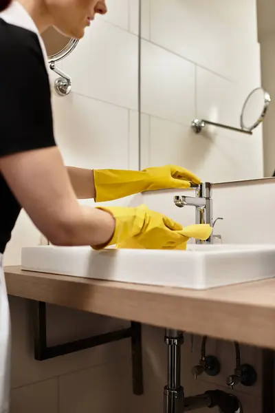 Woman focuses on washing dishes in a clean kitchen with stylish decor and warm lighting. — Stock Photo