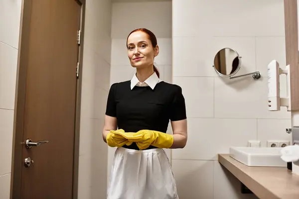 Brightly lit restroom features a young woman smiling, ready to begin her cleaning duty. — Stock Photo