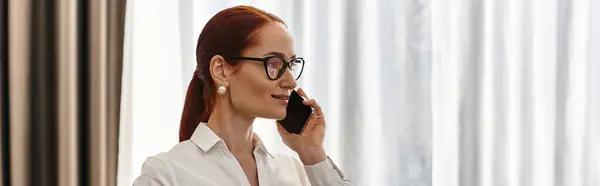 Young woman with glasses talks on the phone, showcasing confidence in a modern environment. — Stock Photo