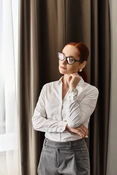 Beautiful woman dressed in white blouse and gray pants reflects quietly by the window. — Stock Photo