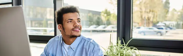 A man with a confident smile focuses on his work while enjoying the view outside. — Stock Photo