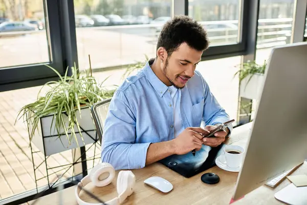 A handsome man smiles as he interacts with his smartphone, coffee beside him. — Stock Photo