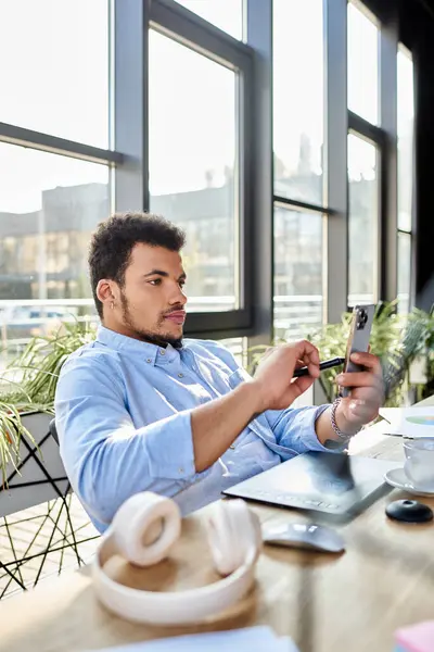 Handsome man sits comfortably at a table, engaged with his phone while sipping coffee. — Stock Photo