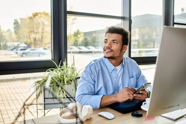A handsome man smiles while using his phone in a bright, contemporary office space. — Stock Photo