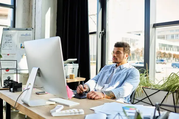 Handsome man engages in creative tasks at an expansive office desk during daylight hours. — Stock Photo