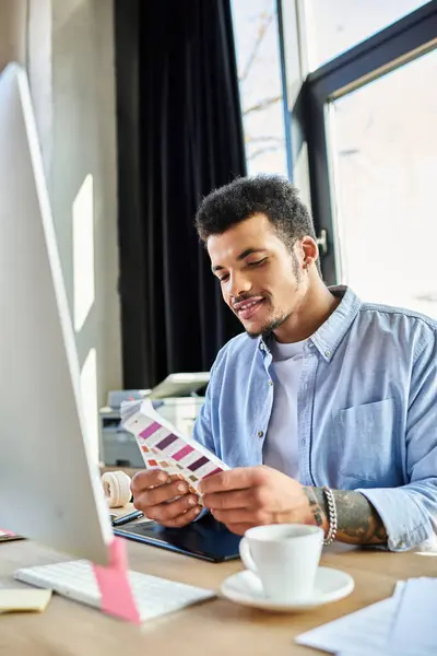 A stylish man examines color swatches thoughtfully at his desk in a modern office setting. — Stock Photo