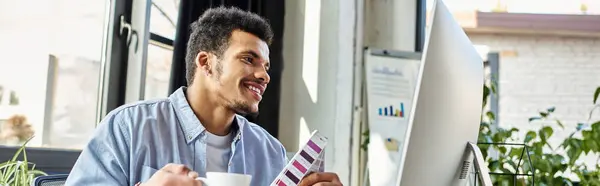 Bright workspace featuring a handsome man focused on his computer while enjoying coffee. — Stock Photo