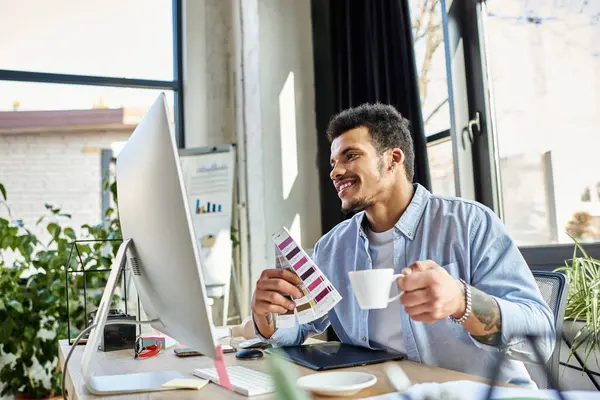 Charming man engaged in design work while sipping coffee in a modern office setting — Stock Photo