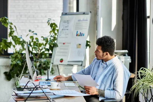 Handsome man analyzes data on a computer while surrounded by greenery in a bright office space. — Stock Photo