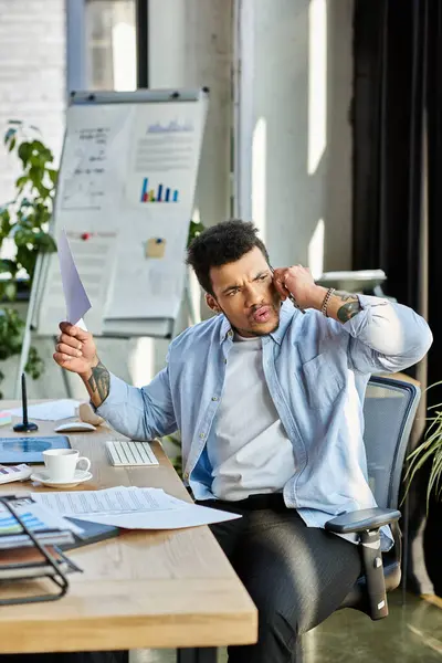 Focused man handles a phone call and paperwork in a vibrant office filled with plants. — Stock Photo