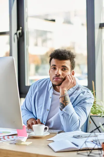 Bell'uomo seduto a una scrivania, a contemplare idee mentre circondato da materiali per ufficio. — Foto stock