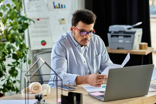 Dedicated man evaluates important papers while working at a creative office filled with plants. — Stock Photo