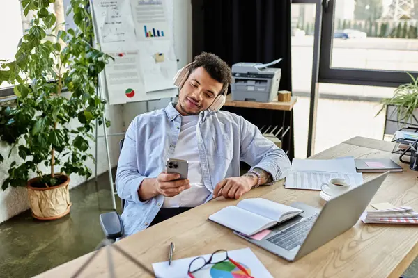 Un hombre tranquilo y elegante disfruta de la música mientras revisa su teléfono en una oficina moderna. - foto de stock