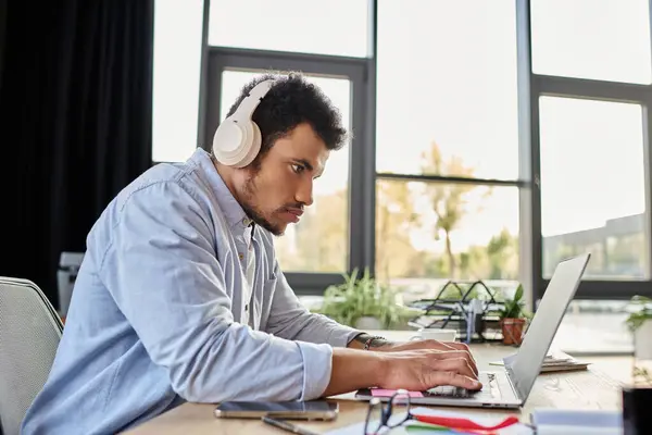 Handsome man engrossed in his work at a stylish desk with plants and natural light. — Stock Photo