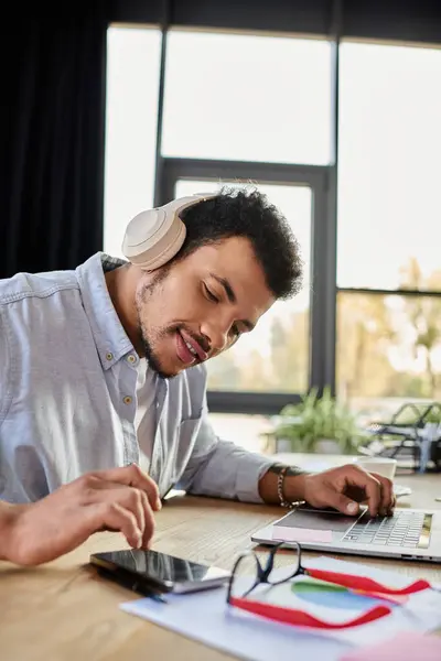 Individuo enfocado disfruta de melodías mientras multitarea en un ambiente de trabajo elegante y brillante - foto de stock