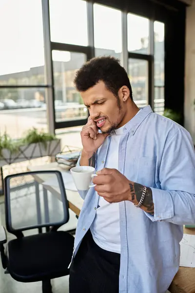Handsome man ponders over a warm cup of coffee in a stylish office setting. — Stock Photo