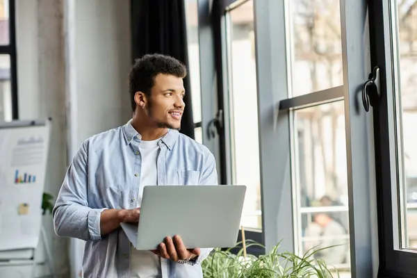 Focused individual engages with laptop indoors, smiling and enjoying the natural light. — Stock Photo