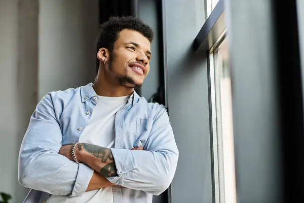 A charming man reflects joyfully while leaning against a window in a contemporary space. — Stock Photo