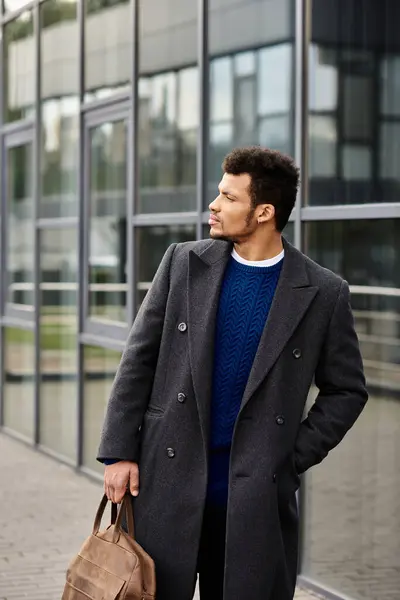 Un hombre bien vestido con una expresión confiada pasea por un edificio de vidrio contemporáneo. - foto de stock