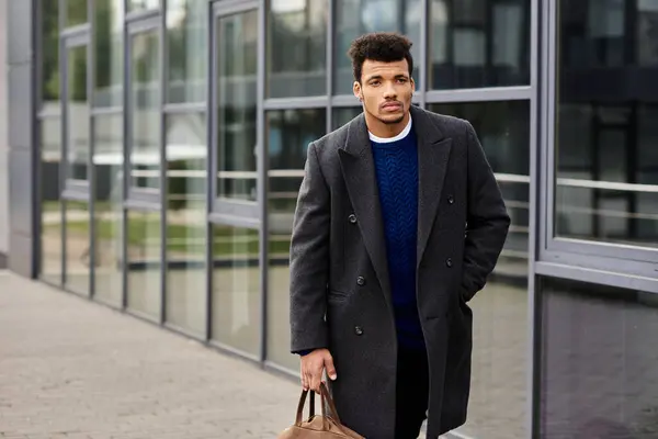 Young man in stylish coat strolls with a bag, showcasing confidence in the city. — Stock Photo
