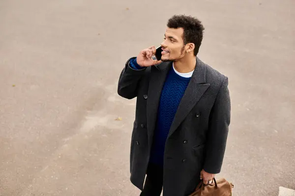 El hombre disfruta de una conversación por teléfono mientras se ve relajado en su atuendo de moda. — Stock Photo