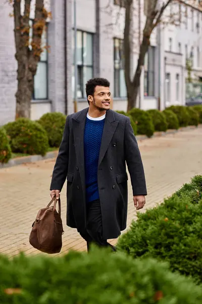 Un hombre bien vestido pasea tranquilamente por un encantador y verde vecindario urbano. - foto de stock