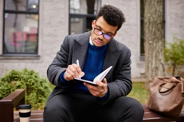 A stylish man enjoys a moment of creativity while writing in a notebook surrounded by nature — Stock Photo