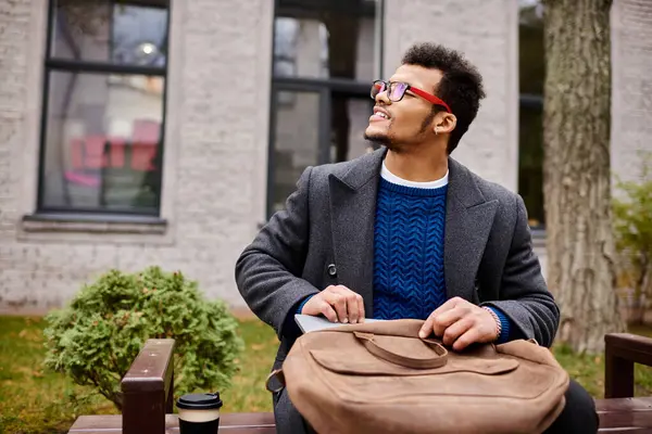 Charming gentleman sits on a bench, smiling while holding a bag in a bustling park. — Stock Photo